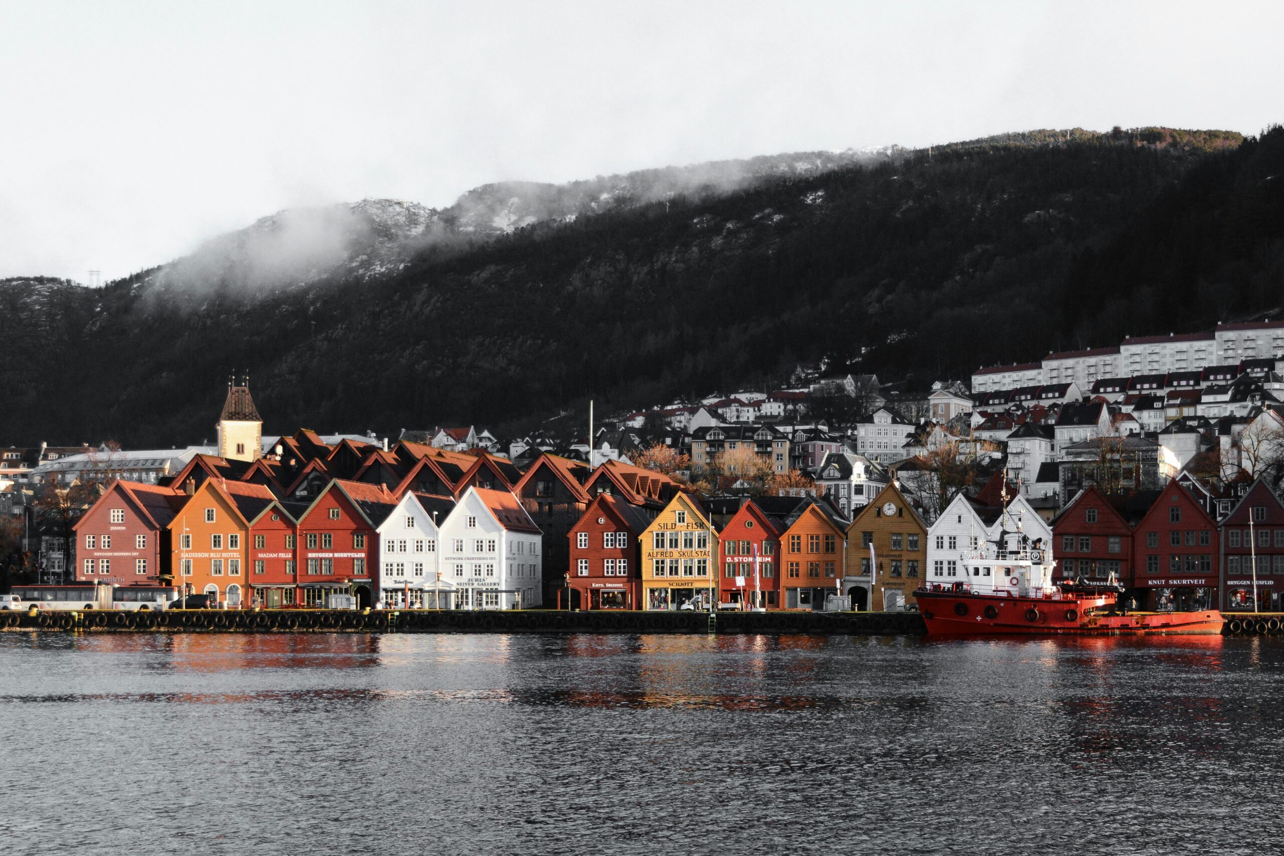 Colorful wooden houses along Bergen harbor framed by misty hills, a classic Scandinavian cityscape in this Scandinavia Travel Guide.
